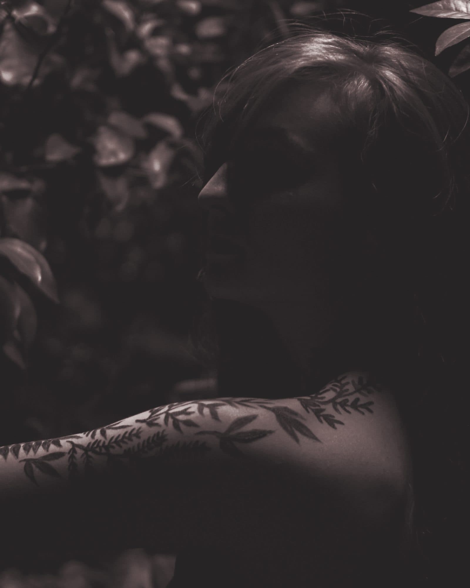 Portrait sombre, bras tatoué de motifs botaniques